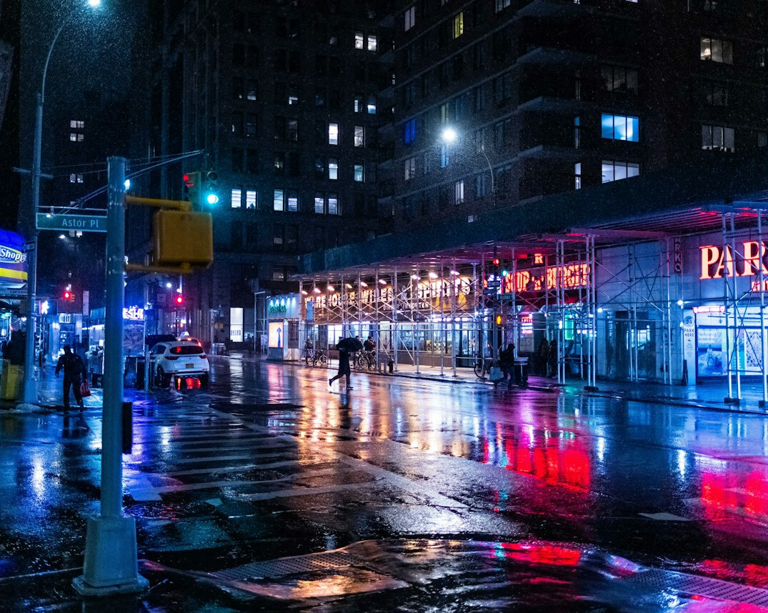 Wet city street at dusk with street lamps